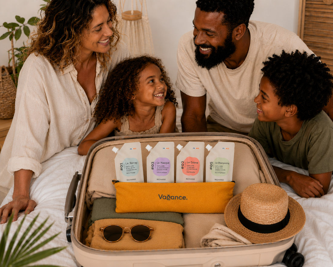 Une famille prépare ses vacances autour d’une valise ouverte contenant une trousse Vagance et quatre recharges de soins capillaires pour cheveux bouclés, frisés et crépus. Une routine minimaliste pour voyager léger avec toute la famille.